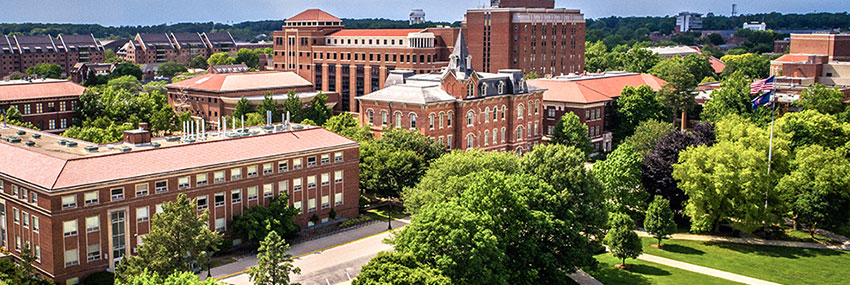Pictured: banner image of drone footage over Purdue's campus, showing many red brick buildings and green lawns